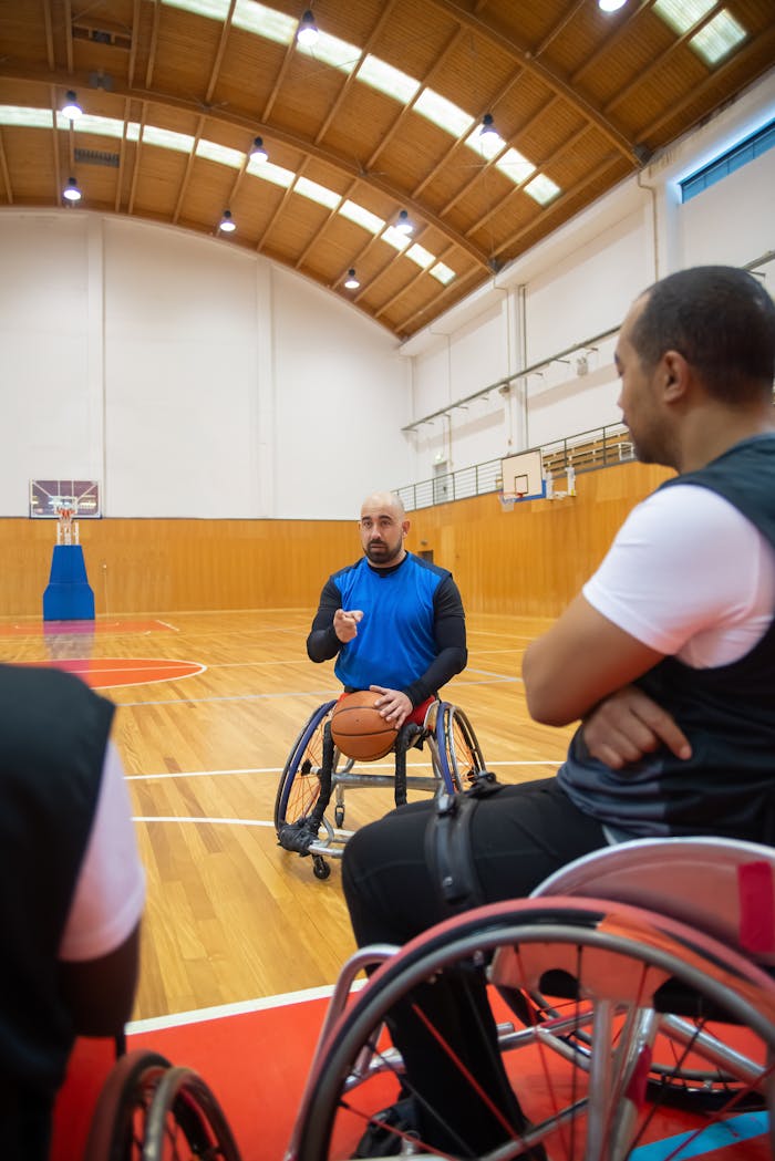 Coach instructing players in an indoor wheelchair basketball court.